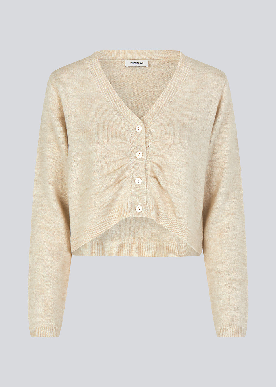 Cropped cardigan i beige i blødt materiale. HeatMD cardigan har v-hals og knaplukning fortil med rynkedetalje. Ærmerne er lange. Modellen er 175 cm og har en størrelse S/36 på.