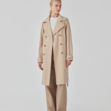 Trenchcoat jakke i beige med i et klassisk udtryk bred krave, bælte i livet og knaplukning. Hiro jacket er perfekt som overgangsjakke fra vinter til forår. Jakken har en rummelig pasform. Vi anbefaler at gå en størrelse ned. Modellen er 174 cm og har en størrelse S/36 på.