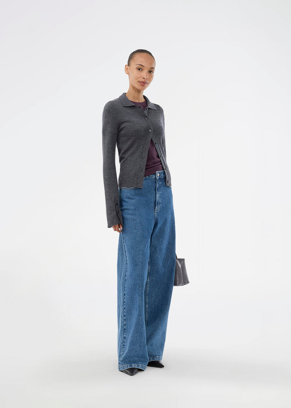 Mørkegrå tætsiddende cardigan i blød ribstrik af uld. HirokiMD cardigan har krave, knapper foran og lange ærmer med slids og knapper. Modellen er 175 cm og har en størrelse S/36 på.