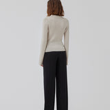 Tætsiddende cardigan io beige i blød ribstrik af uld. HirokiMD cardigan har krave, knapper foran og lange ærmer med slids og knapper. Modellen er 175 cm og har en størrelse S/36 på.