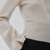 Tætsiddende cardigan io beige i blød ribstrik af uld. HirokiMD cardigan har krave, knapper foran og lange ærmer med slids og knapper. Modellen er 175 cm og har en størrelse S/36 på.