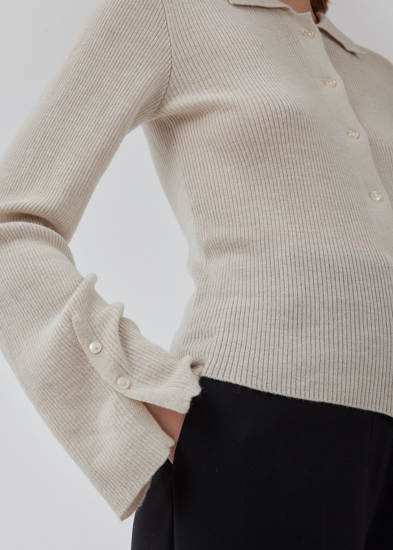 Tætsiddende cardigan io beige i blød ribstrik af uld. HirokiMD cardigan har krave, knapper foran og lange ærmer med slids og knapper. Modellen er 175 cm og har en størrelse S/36 på.