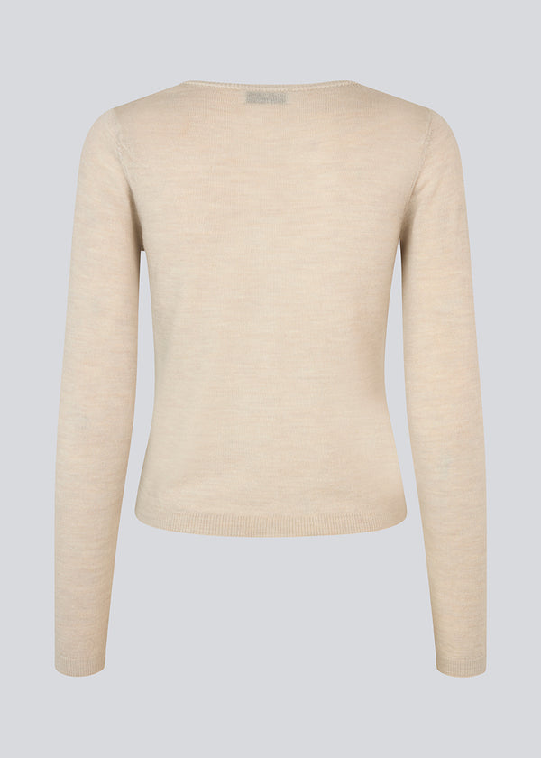 Tætsiddende beige cardigan i blød strik. HirokiMD short cardigan har en rund hals og knappelukning fortil.