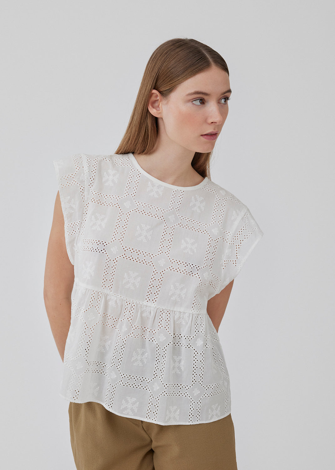 Top i broderie anglaise af bomuld med overskæring under brystet med ekstra vidde. HollynMD top har rund hals, korte ærmer og lille åbning med knap bagpå. Modellen er 175 cm og har en størrelse S/36 på.