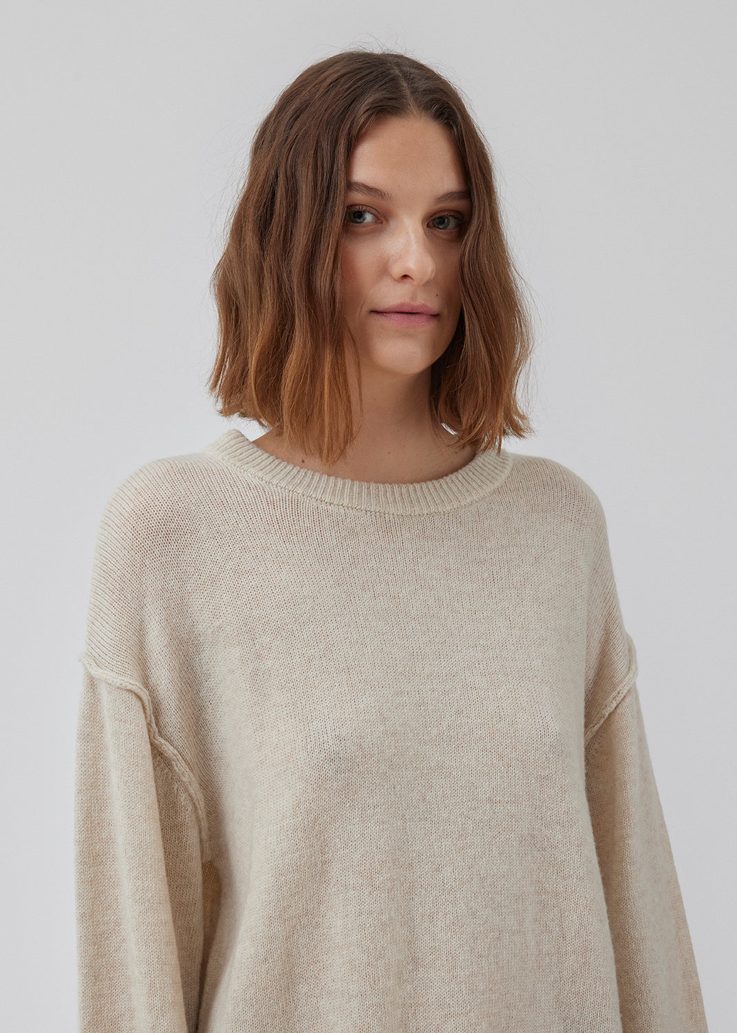 Finstrikket uldtrøje i beige med rund hals og afslappet silhuet med lav skuldersøm med synlige sømdetaljer. HowieMD o-neck har ribstrikkede kanter. Modellen er 175 cm og har en størrelse S/36 på.