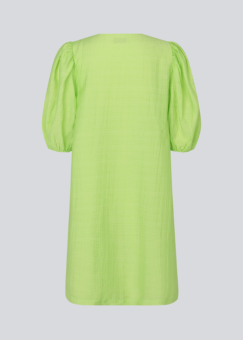 Midi kjole i lime grøn med en løs pasform og V-halsudskæring. IbiMD flare dress har pufærmer i 3/4 ærmelænge med elastik.