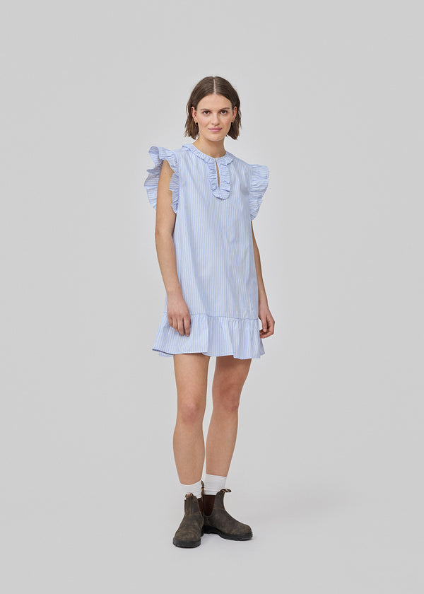 Kort, ærmeløs kjole med flæsedetaljer. InaraMD dress har et hul fortil, som lukkes med en knap og en dekorativ flæsekant. Modellen er 177 cm og har en størrelse S/36 på.