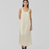 Lang kjole i beige i satin med A-formet silhuet. IolaMD dress har en dyb rygudskæring og brede stropper. Modellen er 177 cm og har en str S/36 på.
