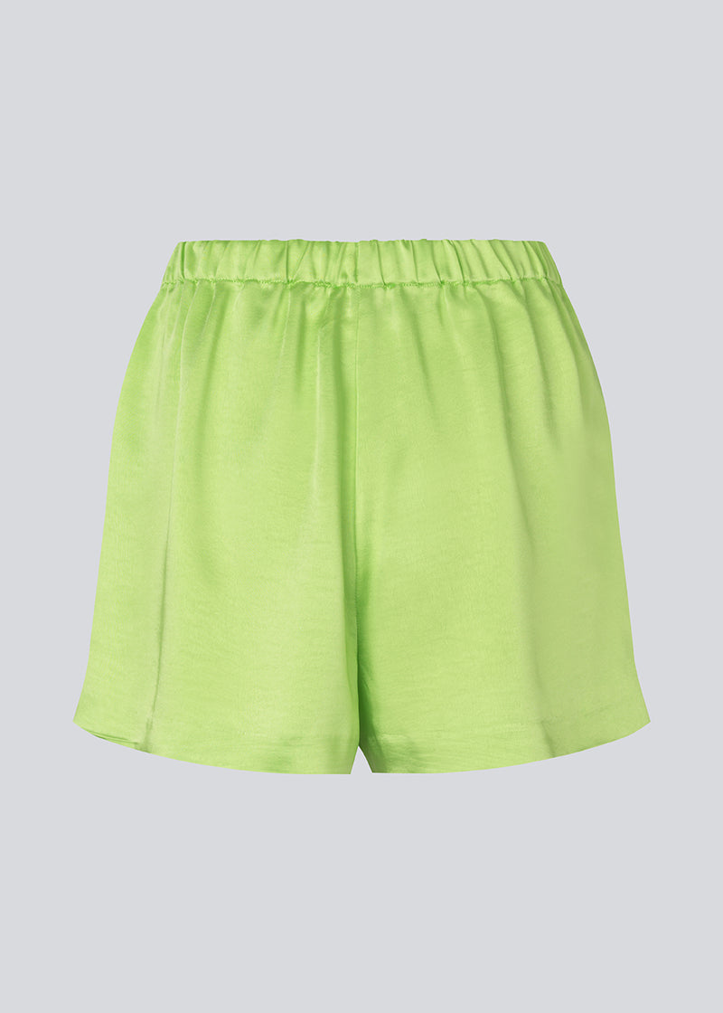 Løse shorts i grøn i satin med elastik i taljen. IolaMD shorts har en mellemhøj taljeog sidelommer. Modellen er 177 cm og har en størrelse S/36 på.