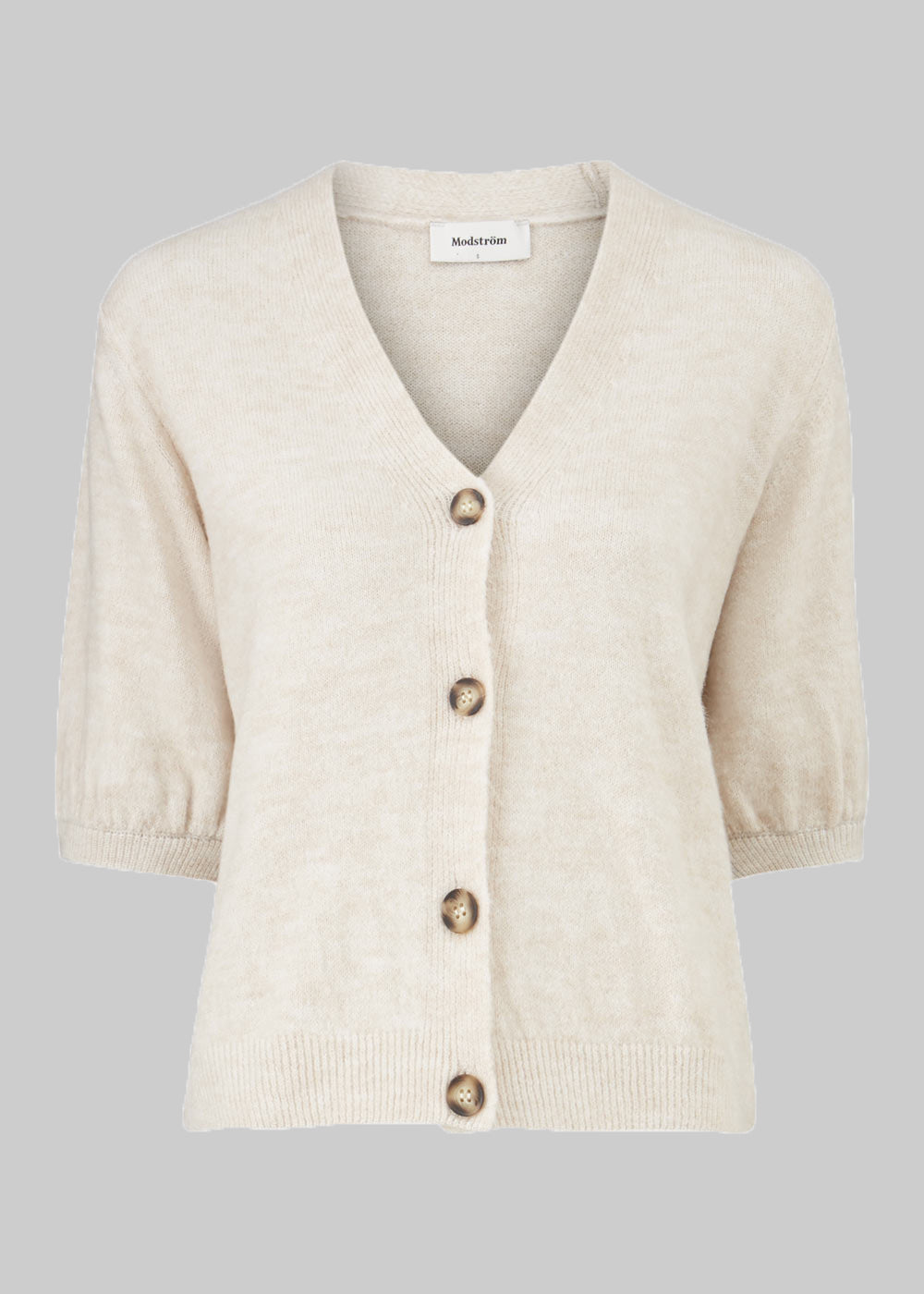 Trendy cardigan i beige med korte pufærmer og knaplukning fortil. Irene cardigan er lavet i et blødt materiale, perfekt til de tidlige forårsdage. Modellen er 174 cm og har en størrelse S/36 på