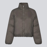Let cropped puffer i en brunlig farve med høj hals. JoniMD jacket har to sidelommer, elastik i bunden af ærmerne og et justerbar snører i bunden.