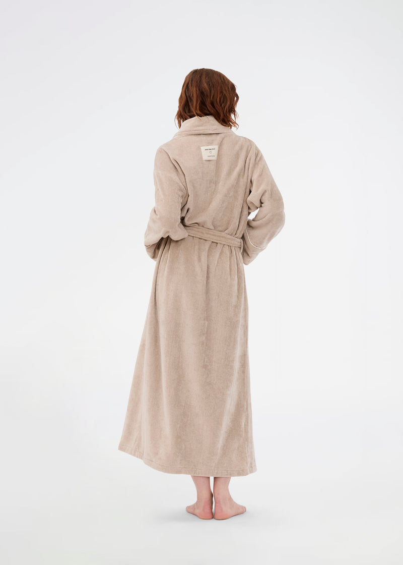 Oversize beige badekåbe i 100% økologisk bomuld. Josefinemd bathrobe har store lommer, bindebånd og kontrastkanter, der giver den et elegant touch. Badekåben har et fint og diskret logo på ryggen. Perfekt til hyggelige morgener. Josefine Vogt (165 cm) og modellen (177 cm) har begge størrelse Small på.