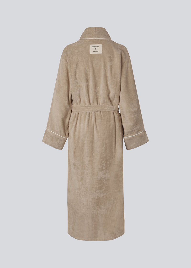 Oversize beige badekåbe i 100% økologisk bomuld. Josefinemd bathrobe har store lommer, bindebånd og kontrastkanter, der giver den et elegant touch. Badekåben har et fint og diskret logo på ryggen. Perfekt til hyggelige morgener. Josefine Vogt (165 cm) og modellen (177 cm) har begge størrelse Small på.