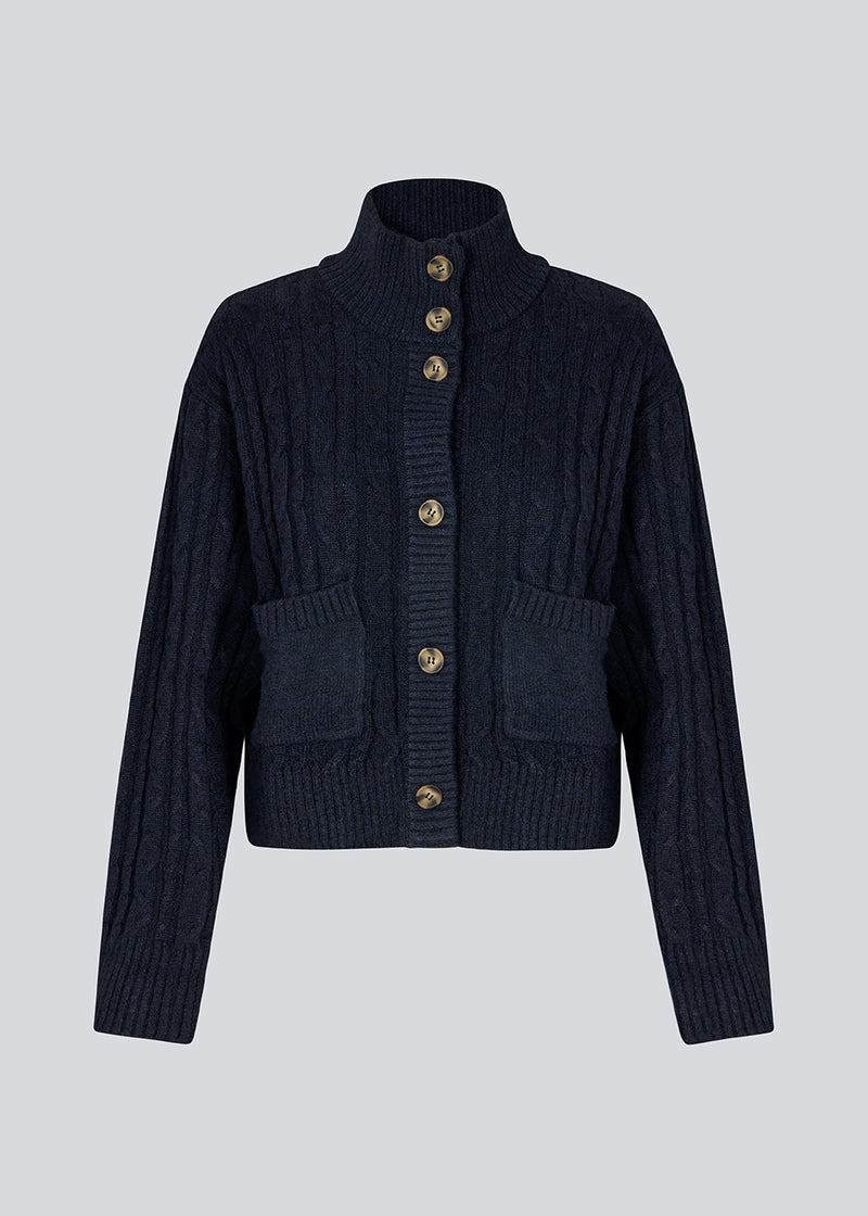 Højhalset cardigan. Josefinemd knit cardigan er kabelstrikket med høj hals, manchetknapper og lommer. Tidløs og perfekt til kølige dage, eller som layering over kjoler og toppe.&nbsp;
Josefine Vogt (165 cm) og modellen (177 cm) har begge størrelse Small på.