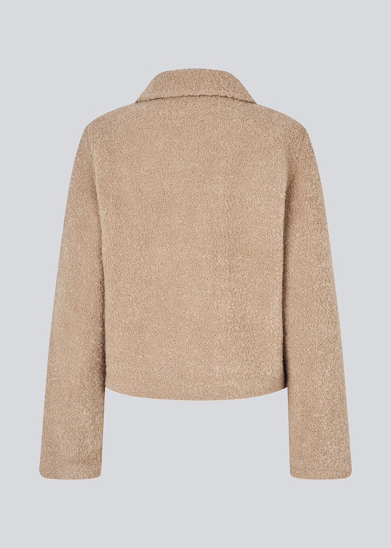 Kort beige jakke i uldblanding. JustyMD short jacket har en løs pasform, knappelukning og to lommer fortil.