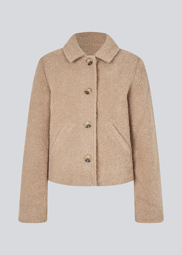 Kort beige jakke i uldblanding. JustyMD short jacket har en løs pasform, knappelukning og to lommer fortil.