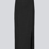 Lang glatstrikket nederdel i sort med foldede detaljer. KaitoMD skirt en elastisk talje og en slids fortil.
