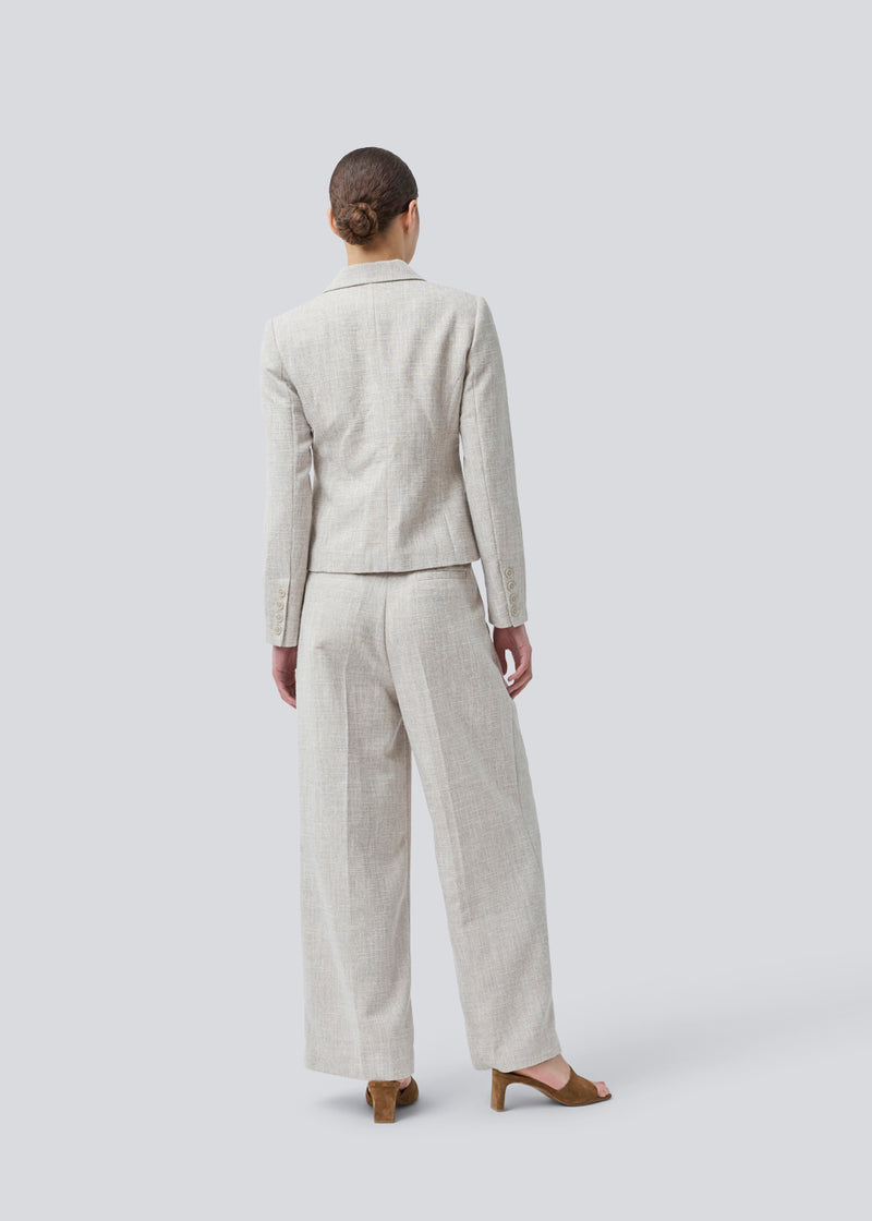Vores meget populære Kiera jakkesæt er tilbage i en ny sommer-farve.
Kort figursyet blazer i beige melange i et tykt struktureret materiale. KieraMD jacket har knappelukning, to lommer foran og en slids i ærmet som spændes med knapper.