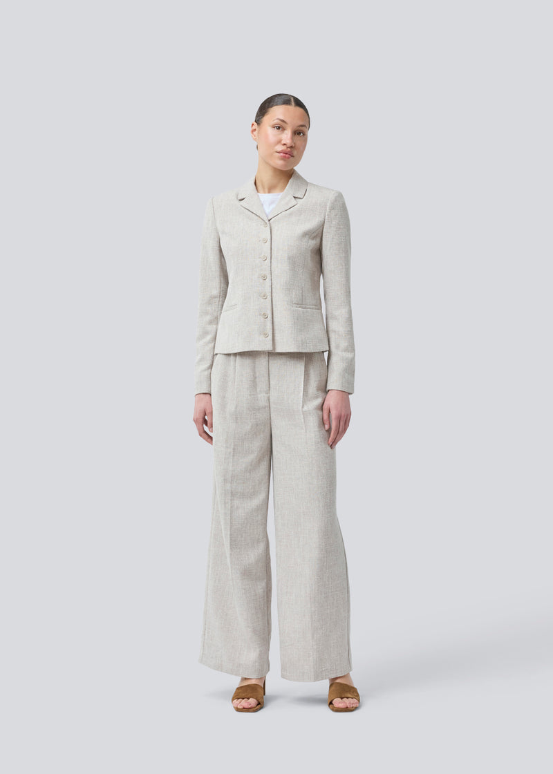 Vores meget populære Kiera jakkesæt er tilbage i en ny sommer-farve.
Kort figursyet blazer i beige melange i et tykt struktureret materiale. KieraMD jacket har knappelukning, to lommer foran og en slids i ærmet som spændes med knapper.