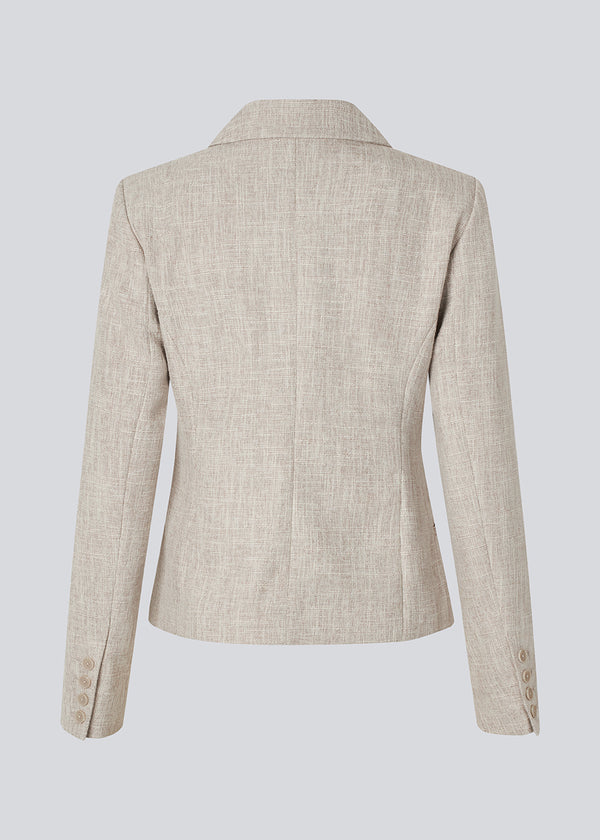 Vores meget populære Kiera jakkesæt er tilbage i en ny sommer-farve.
Kort figursyet blazer i beige melange i et tykt struktureret materiale. KieraMD jacket har knappelukning, to lommer foran og en slids i ærmet som spændes med knapper.