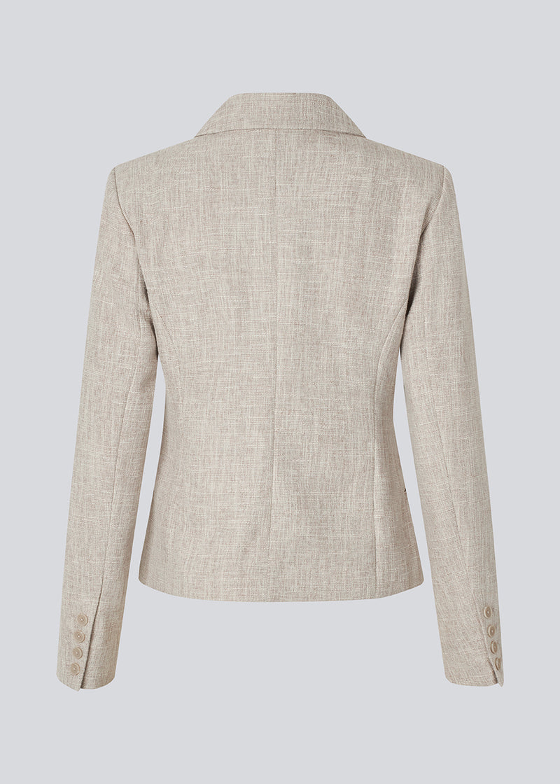Vores meget populære Kiera jakkesæt er tilbage i en ny sommer-farve.
Kort figursyet blazer i beige melange i et tykt struktureret materiale. KieraMD jacket har knappelukning, to lommer foran og en slids i ærmet som spændes med knapper.