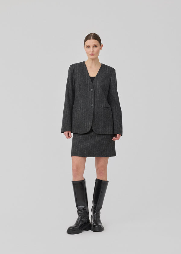 Kort mørkegrå stribet nederdel i uldblanding. KristolMD skirt har foer og en usynlig lynlås i siden. Modellen er 175 cm og bruger størrelse S.