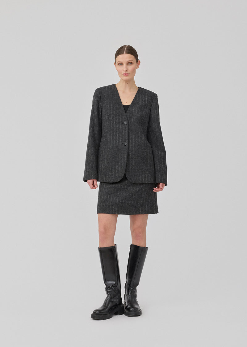 Kort mørkegrå stribet nederdel i uldblanding. KristolMD skirt har foer og en usynlig lynlås i siden. Modellen er 175 cm og bruger størrelse S.
