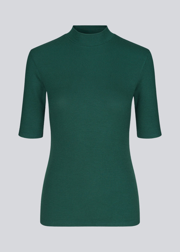 Kortærmet t-shirt med høj hals. Krown t-shirt i farven bottle green er en Modström klassiker i rib kvalitet og er tætsiddende i pasformen.
