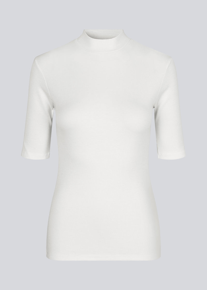 Kortærmet hvid t-shirt med høj hals. Krown t-shirt i farven Porcelain er i rib kvalitet og er tætsiddende i pasformen. Krown t-shirt er en klassiker i enhver garderobe.  Modellen er 177 cm og har en størrelse S/36 på.