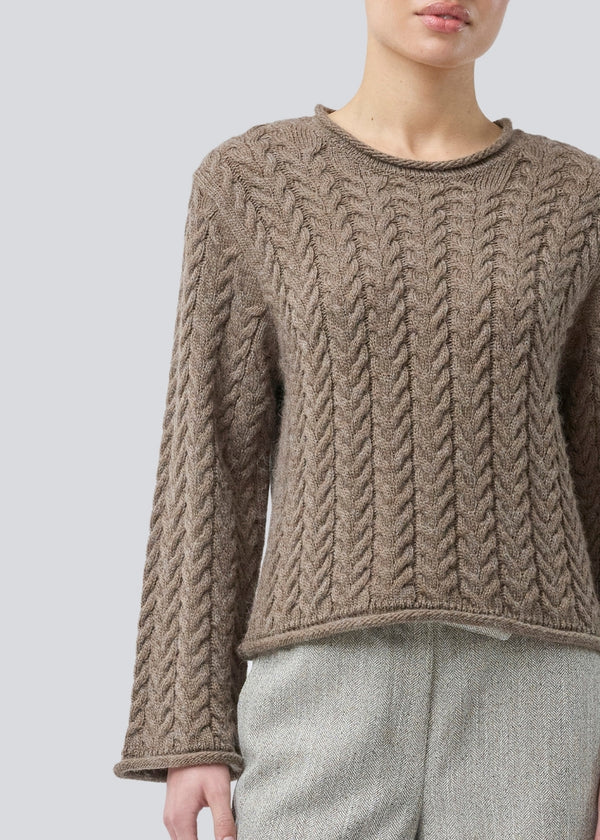 Løs strik med brede ærmer i kabel strik. KurtisMD v-neck har en rund halsudskæring og rullede detaljer på ærmerne og halsen.