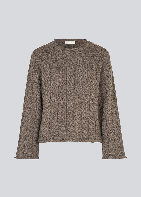 Løs strik med brede ærmer i kabel strik. KurtisMD v-neck har en rund halsudskæring og rullede detaljer på ærmerne og halsen.