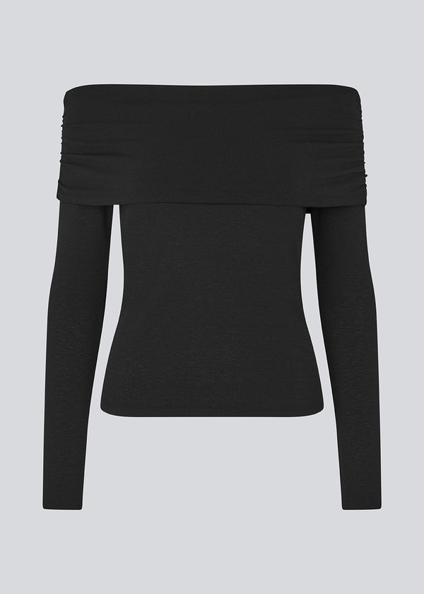 Sort off shoulder top i et elastisk materiale. LillianMD top er figursyet og har lange tætsiddende ærmer. Modellen er 177 cm og har en størrelse S/36 på.