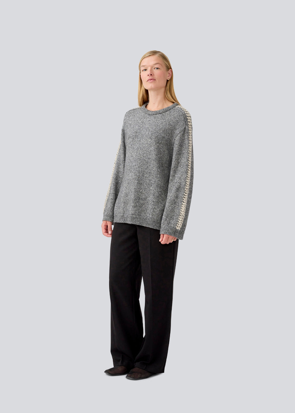 Blød mørkegrå strik med beige detalje på ærmet. LineMD o-neck har en rund hals og en løs pasform, samt slidser i siderne. Modellen er 177 cm og har en størrelse S/36 på.