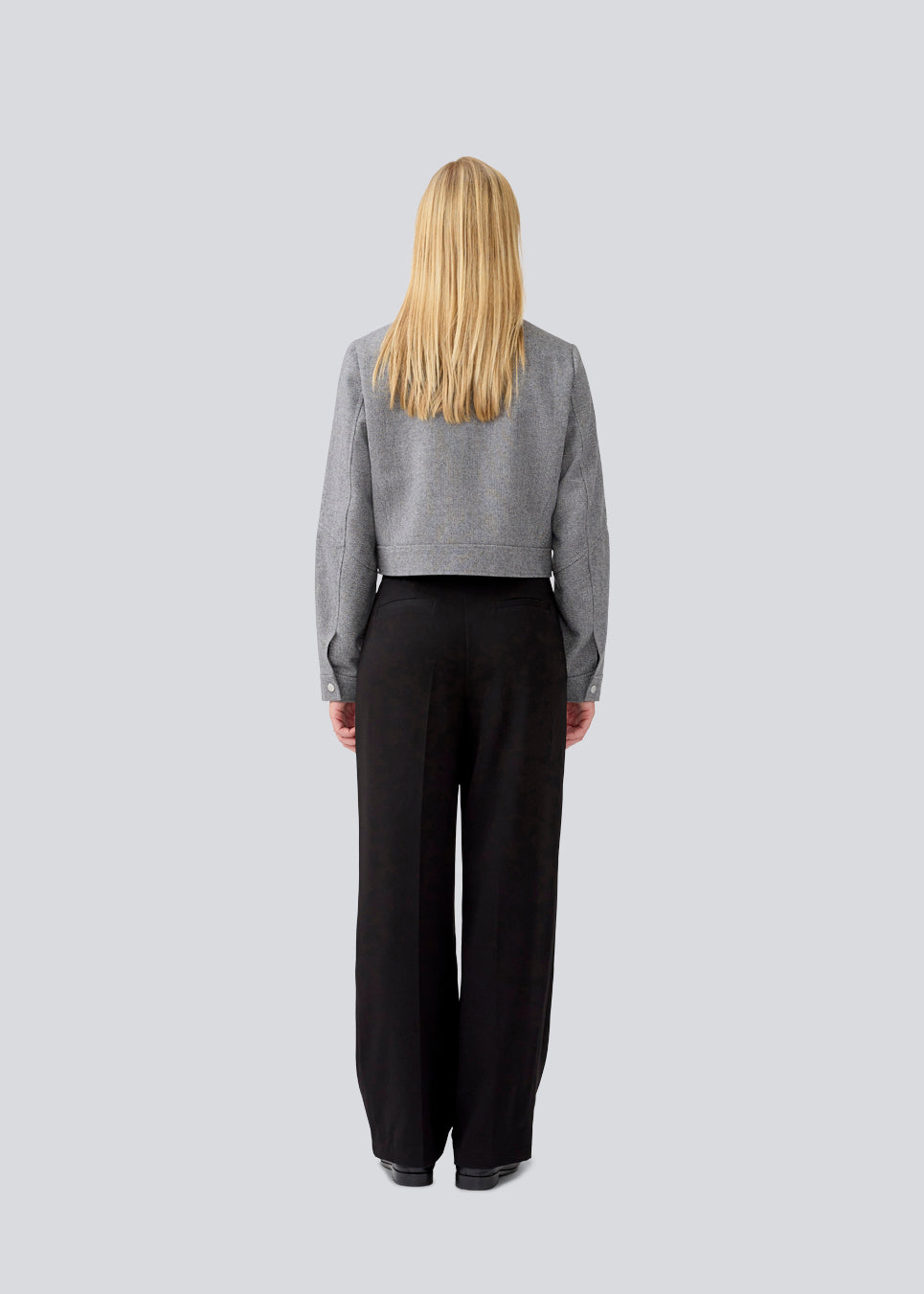 Let cropped jakke i 80% uld. LissieMD jacket er grå, har en klassisk krave, lynlås lukning fortil og manchet med trykknap. Modellen er 177 cm og har en størrelse S/36 på.