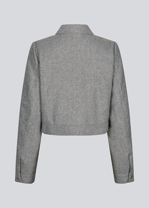 Let cropped jakke i 80% uld. LissieMD jacket er grå, har en klassisk krave, lynlås lukning fortil og manchet med trykknap. Modellen er 177 cm og har en størrelse S/36 på.