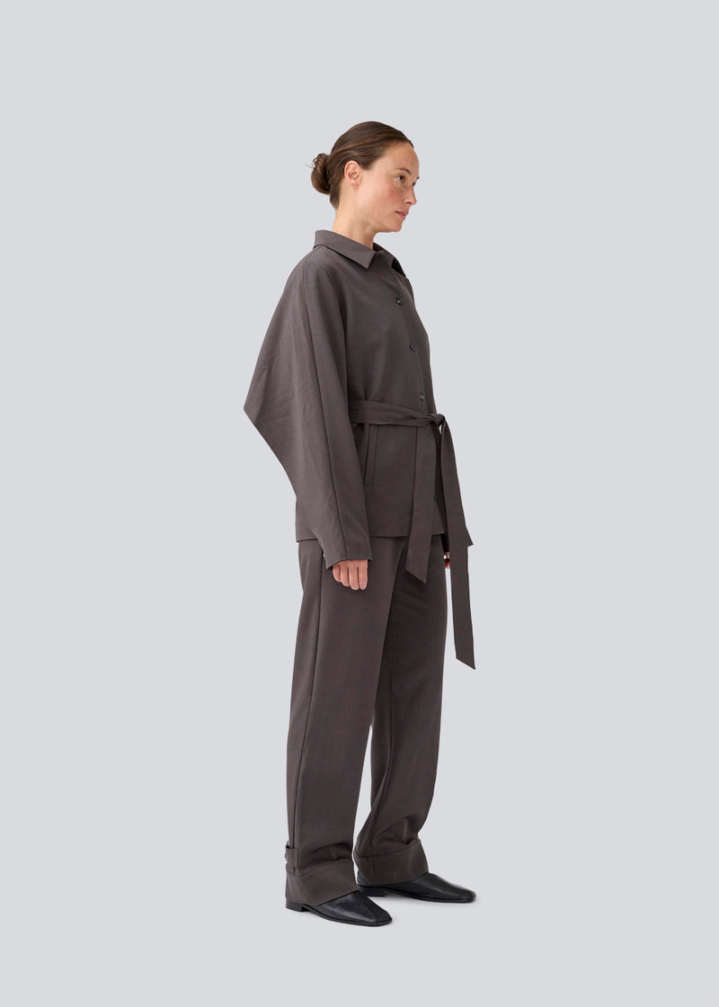 Klassisk mørkegrå blazer med skjorte krave og bindebånd. LonnieMD blazer har to lommer, knappelukning fortil samt et dekorativt bærestykke på ryggen.