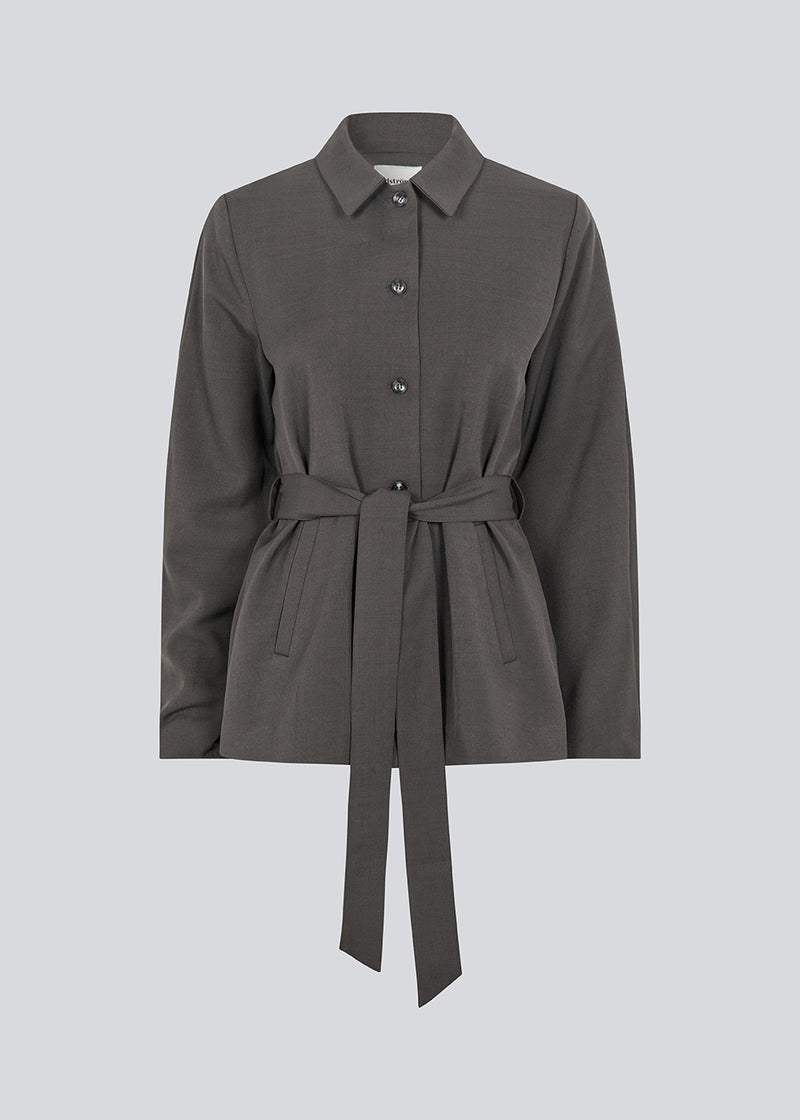 Klassisk mørkegrå blazer med skjorte krave og bindebånd. LonnieMD blazer har to lommer, knappelukning fortil samt et dekorativt bærestykke på ryggen.