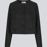 Kort sort jakke i struktureret materiale. LuniMD jacket har to lommer fortil og knappelukning med beklædte knapper. Modellen er 177 cm og har en størrelse S/36 på.