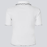 Figursyet polo t-shirt i hvid med sorte kanter i jersey. MagdaloneMD polo har korte ærmer og overlockede kanter. Modellen er 177 cm og har en str. S/36 på.