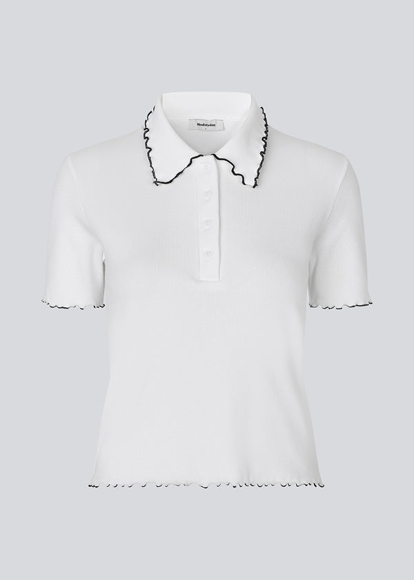 Figursyet polo t-shirt i hvid med sorte kanter i jersey. MagdaloneMD polo har korte ærmer og overlockede kanter. Modellen er 177 cm og har en str. S/36 på.
