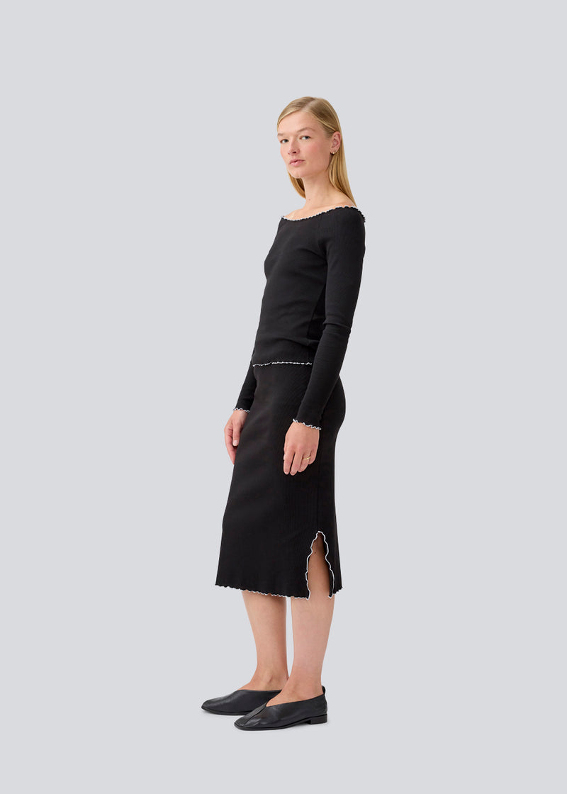 Knælang nederdel i jersey. MagdaloneMD skirt har slidser i siderne og overlockede kanter med elastik i taljen. Modellen er 177 cm og har en str S/36 på.