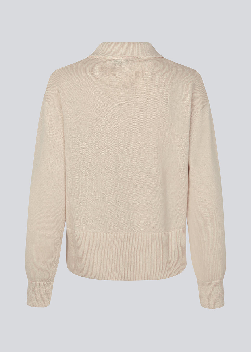 Blød strikket polo i beige. MalvaMD polo har en krave med stolpe lukning. Strikken er lille i størrelsen, og kort. Modellen er 177 cm og har en str S/36 på.