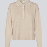 Blød strikket polo i beige. MalvaMD polo har en krave med stolpe lukning. Strikken er lille i størrelsen, og kort. Modellen er 177 cm og har en str S/36 på.