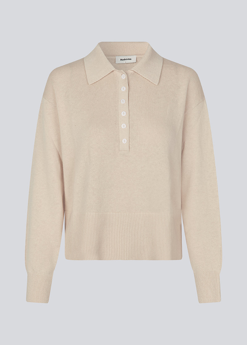 Blød strikket polo i beige. MalvaMD polo har en krave med stolpe lukning. Strikken er lille i størrelsen, og kort. Modellen er 177 cm og har en str S/36 på.