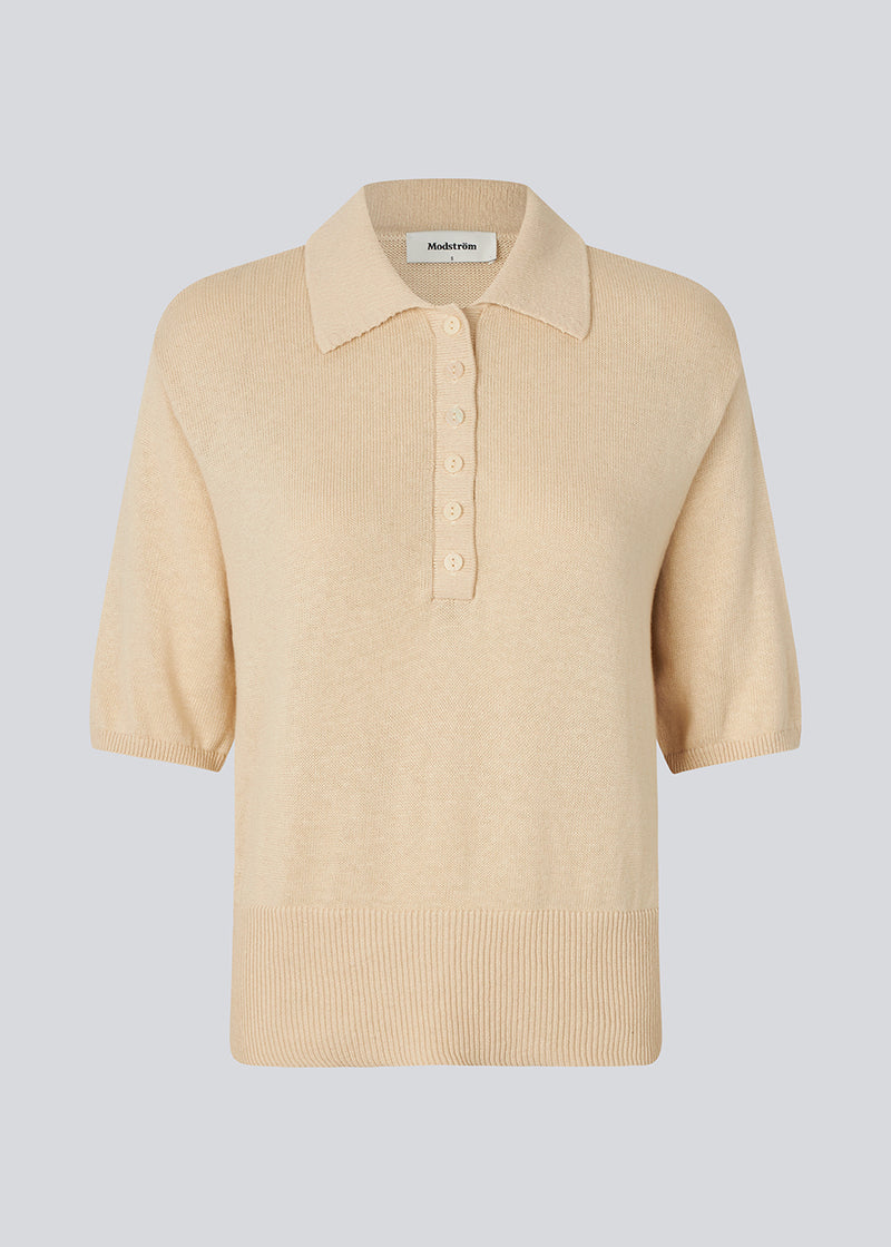 Blød strikket polo i beige i 100% bomuld. MalvaMD SS polo har en krave med stolpelukning og korte ærmer.