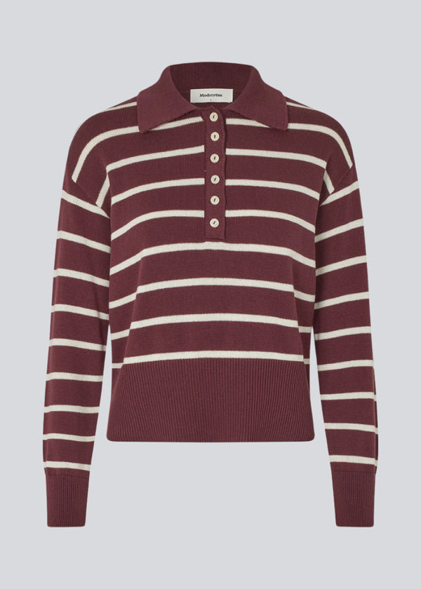 Blød strikket polo i bordeaux/mørkerød med hvide striber. MalvaMD stripe polo har en krave med stolpe lukning. Strikken er lille i størrelsen, og kort.