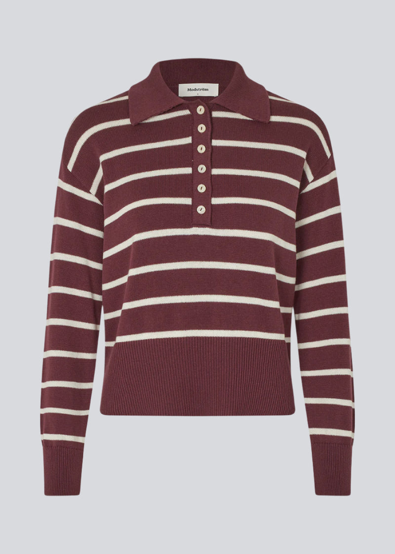 Blød strikket polo i bordeaux/mørkerød med hvide striber. MalvaMD stripe polo har en krave med stolpe lukning. Strikken er lille i størrelsen, og kort.