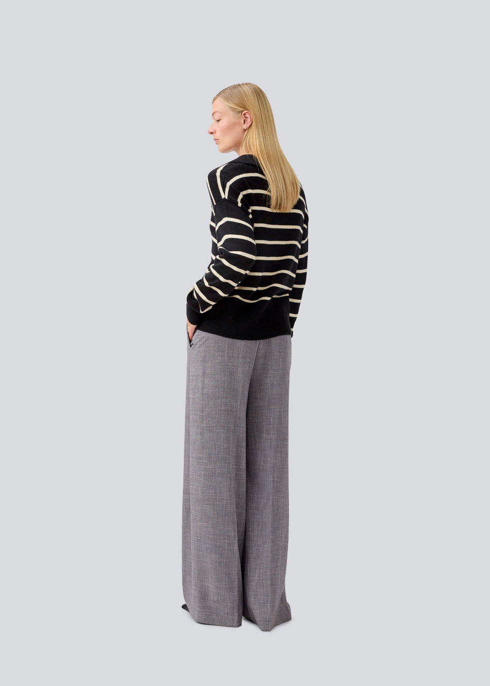Blød strikket polo i sort med beige striber. MalvaMD stripe polo har en krave med stolpelukning. Modellen er 177 cm og har en str S/36 på. Strikken er lille i størrelsen, og kort.