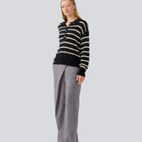 Blød strikket polo i sort med beige striber. MalvaMD stripe polo har en krave med stolpelukning. Modellen er 177 cm og har en str S/36 på. Strikken er lille i størrelsen, og kort.