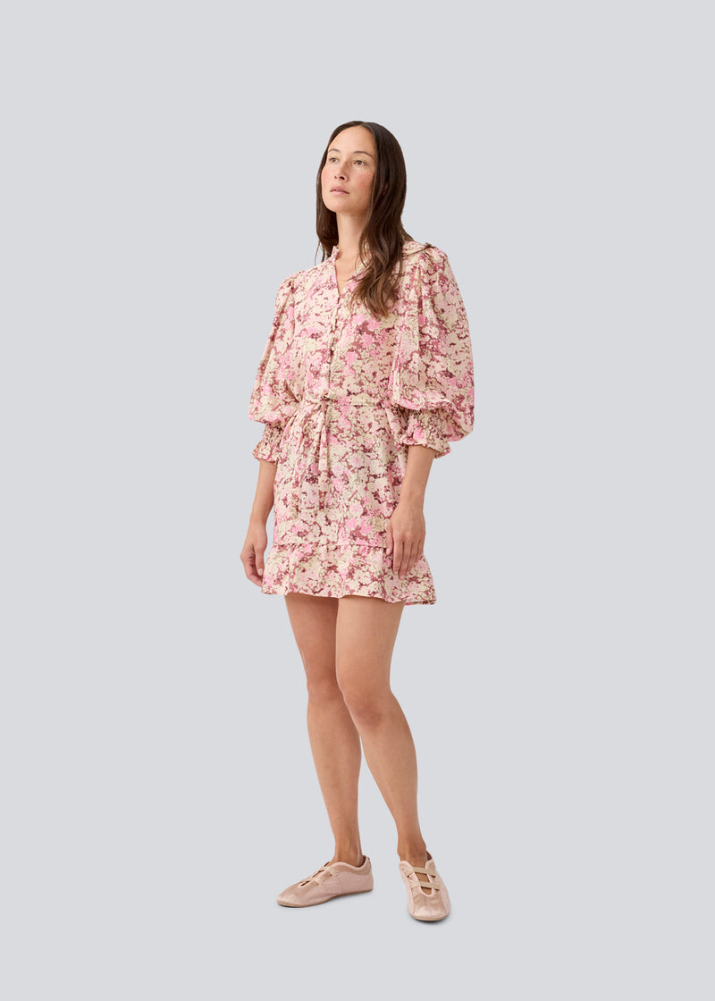 Kort langærmet kjole med v-hals og bindebånd i taljen. MeliaMD print LS dress har en smock detalje ved ærmerne og en flæsekant. Kjolen har et smukt blomstret print i lyserøde nuancer. Modellen er 177 cm og har en str. S/36 på.